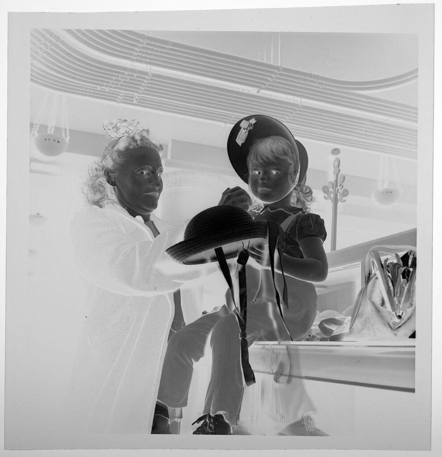 Untitled (seated child trying on hats in store) by Jack Gould