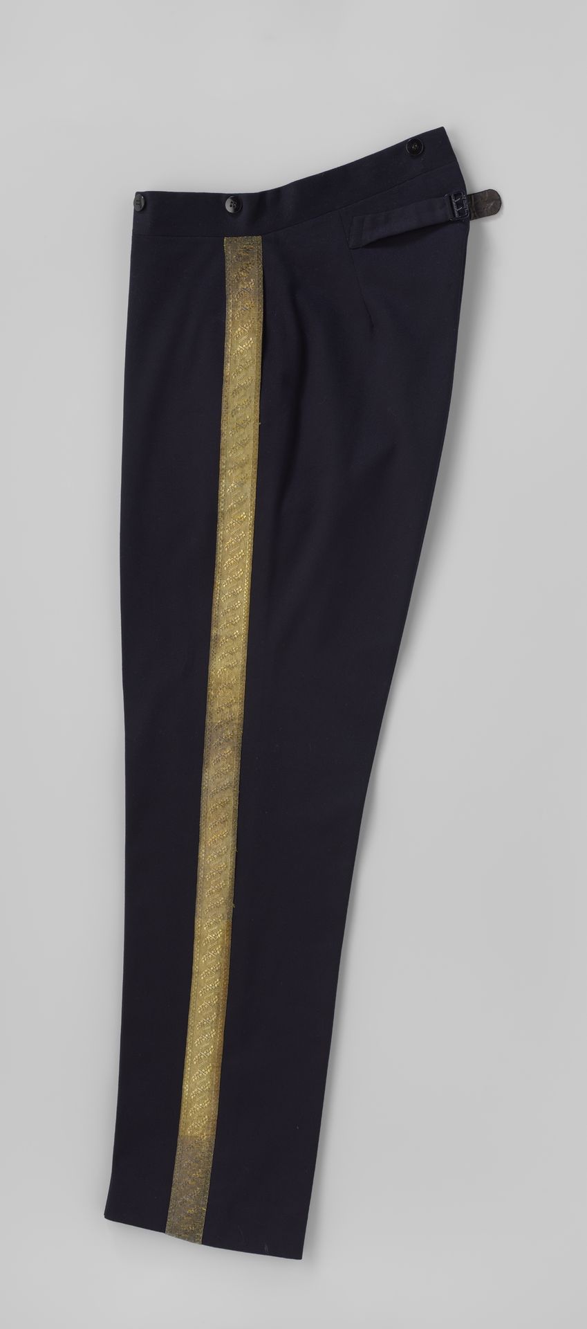 Broek van donkerblauw laken met goudkleurig sierband op de zijnaden by De (firma) Jong