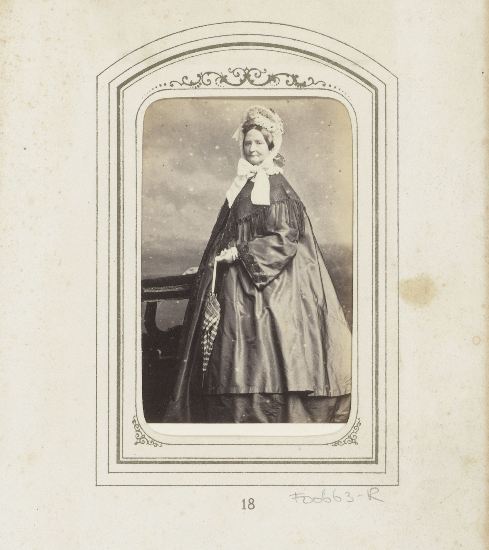 Portret van een staande vrouw met witte muts met linten en paraplu by Wegner & Mottu