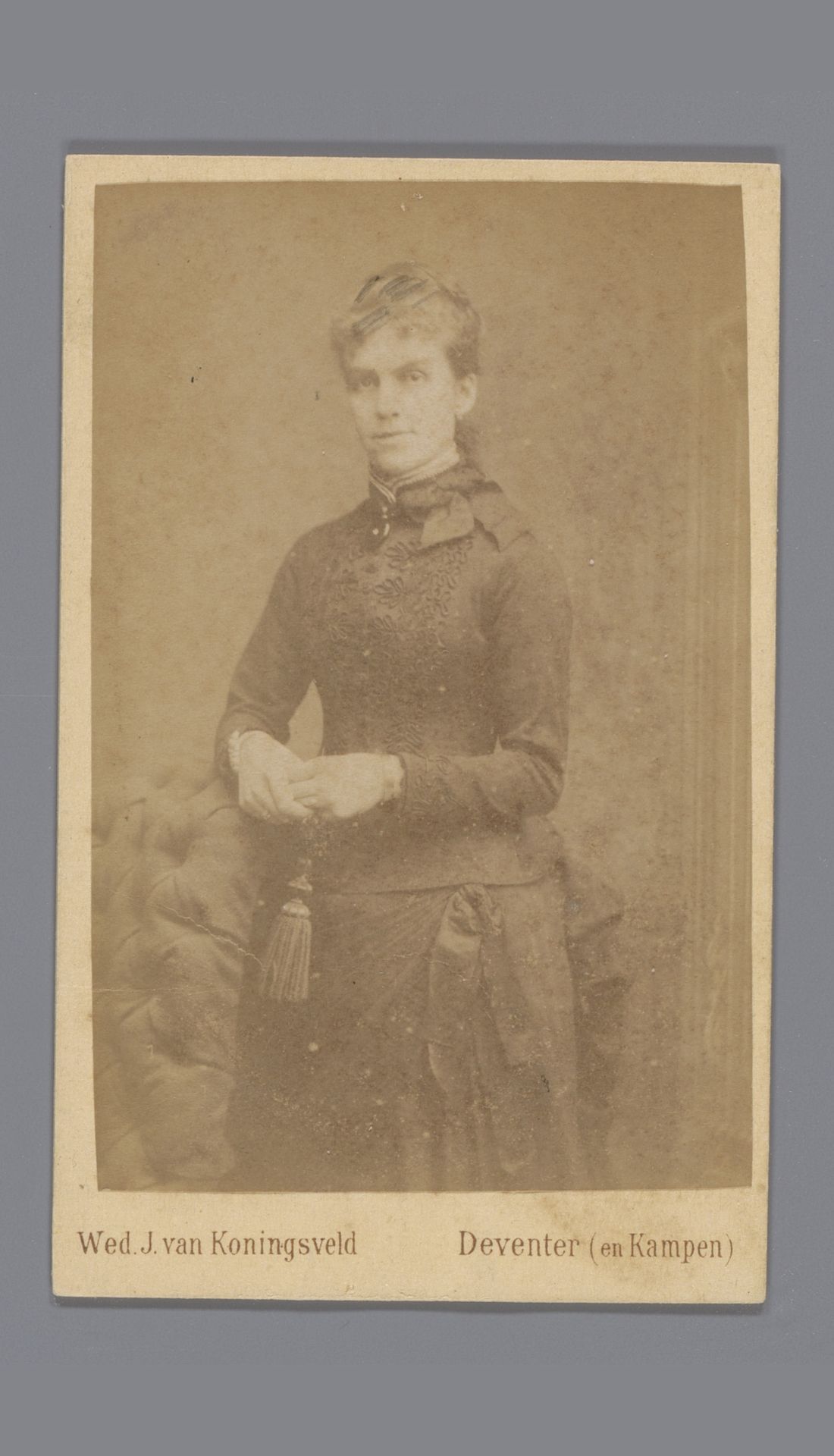 Portret van een onbekende vrouw, staande naast een fauteuil by Veuve J. van Koningsveld