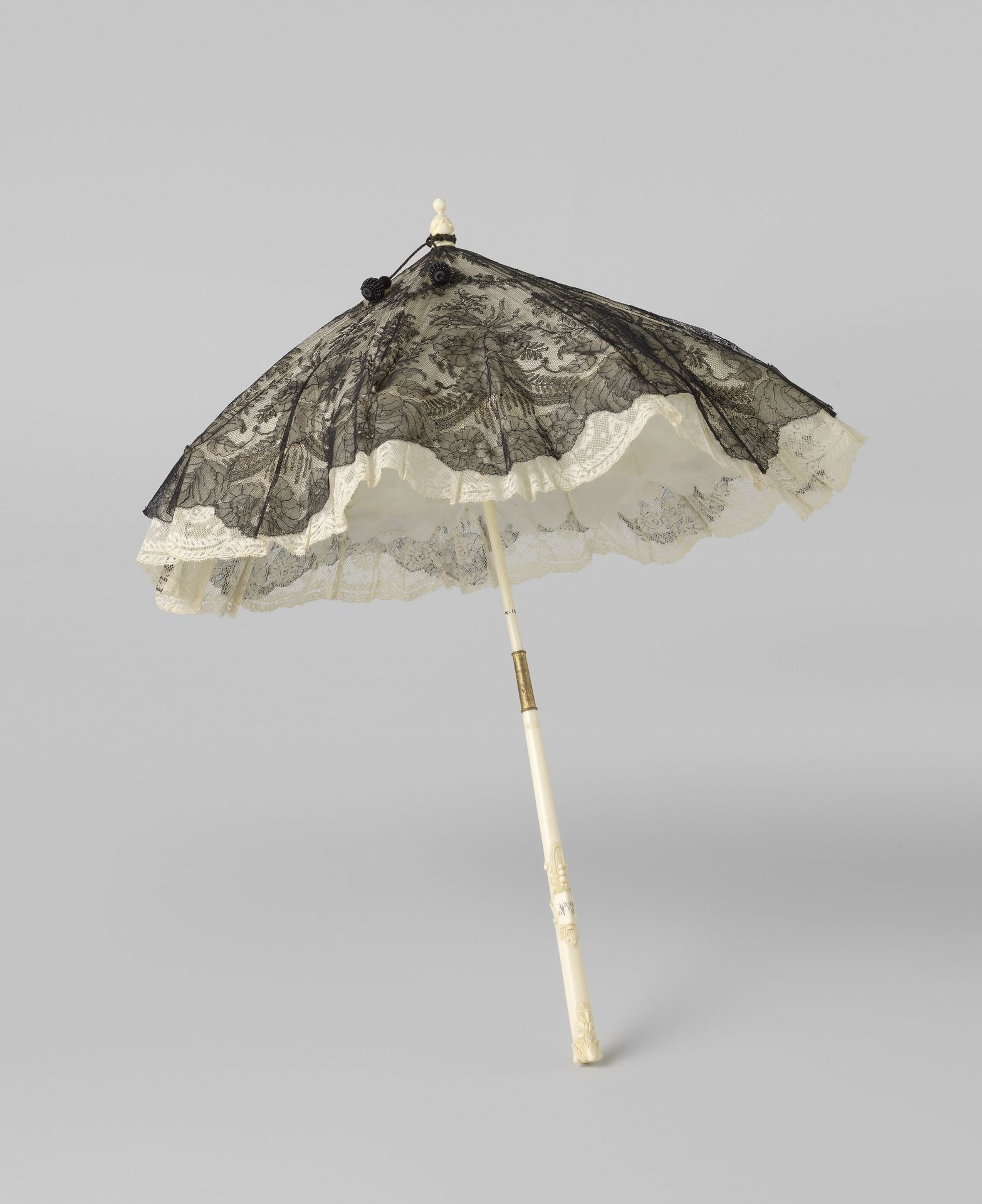 Parasol met een dek van Chantillykant afgezet met een strook witte katoenen kloskant en gevoerd met witte tafzijde op een stok van gesneden ivoor waarop de initialen 'EVN' by Anonymous
