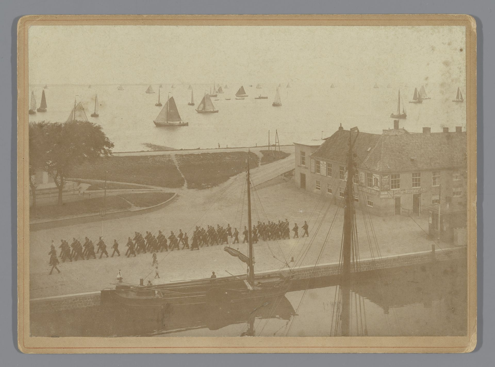 Gezicht op marcherende militairen en zeilschepen in de haven van Den Helder by Anna Clasina Leijer