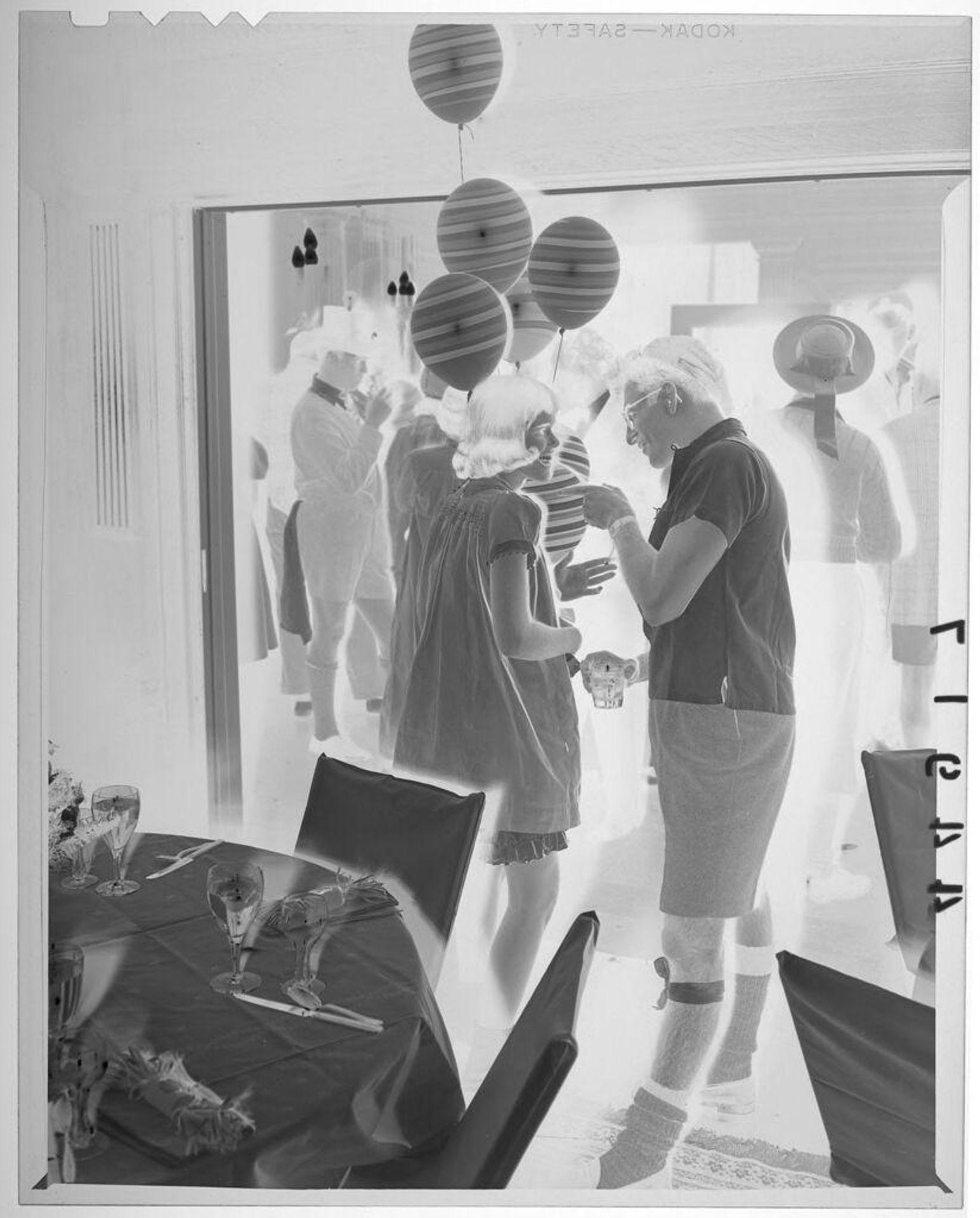 Untitled (young couple in costumes chatting at party with balloons behind them) by Martin Schweig