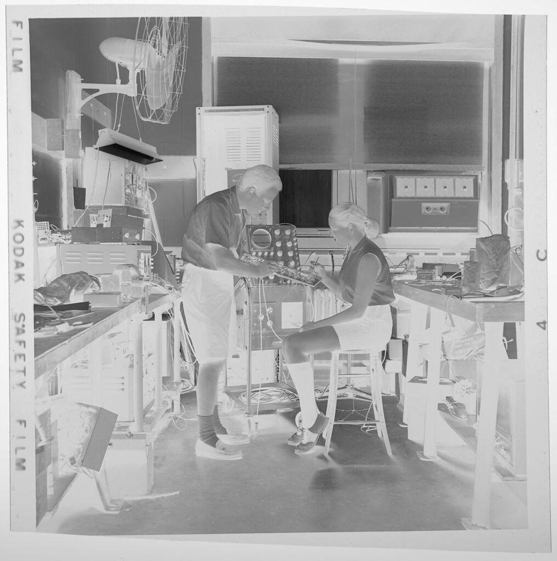 Untitled (student wearing shorts and saddle shoes in science classroom with teacher) by Jack Gould