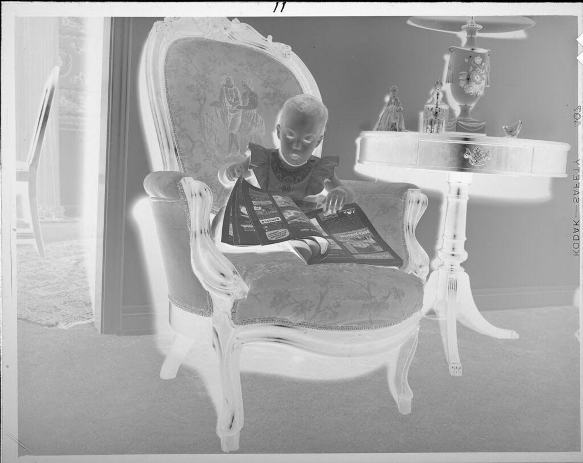 Untitled (baby on armchair with magazine) by Lucian and Mary Brown