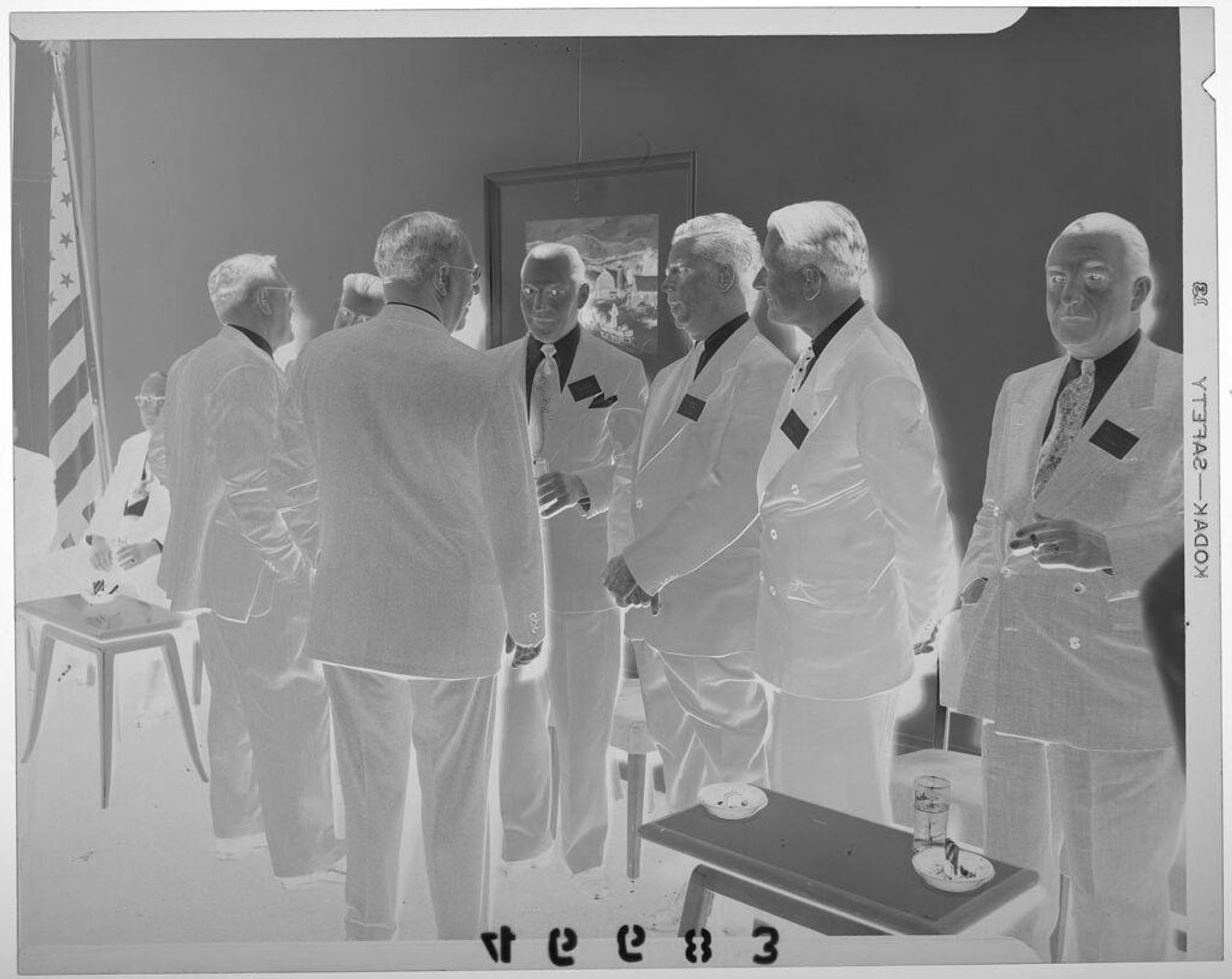 Untitled (seven men wearing name tags chatting in conference hall) by Martin Schweig