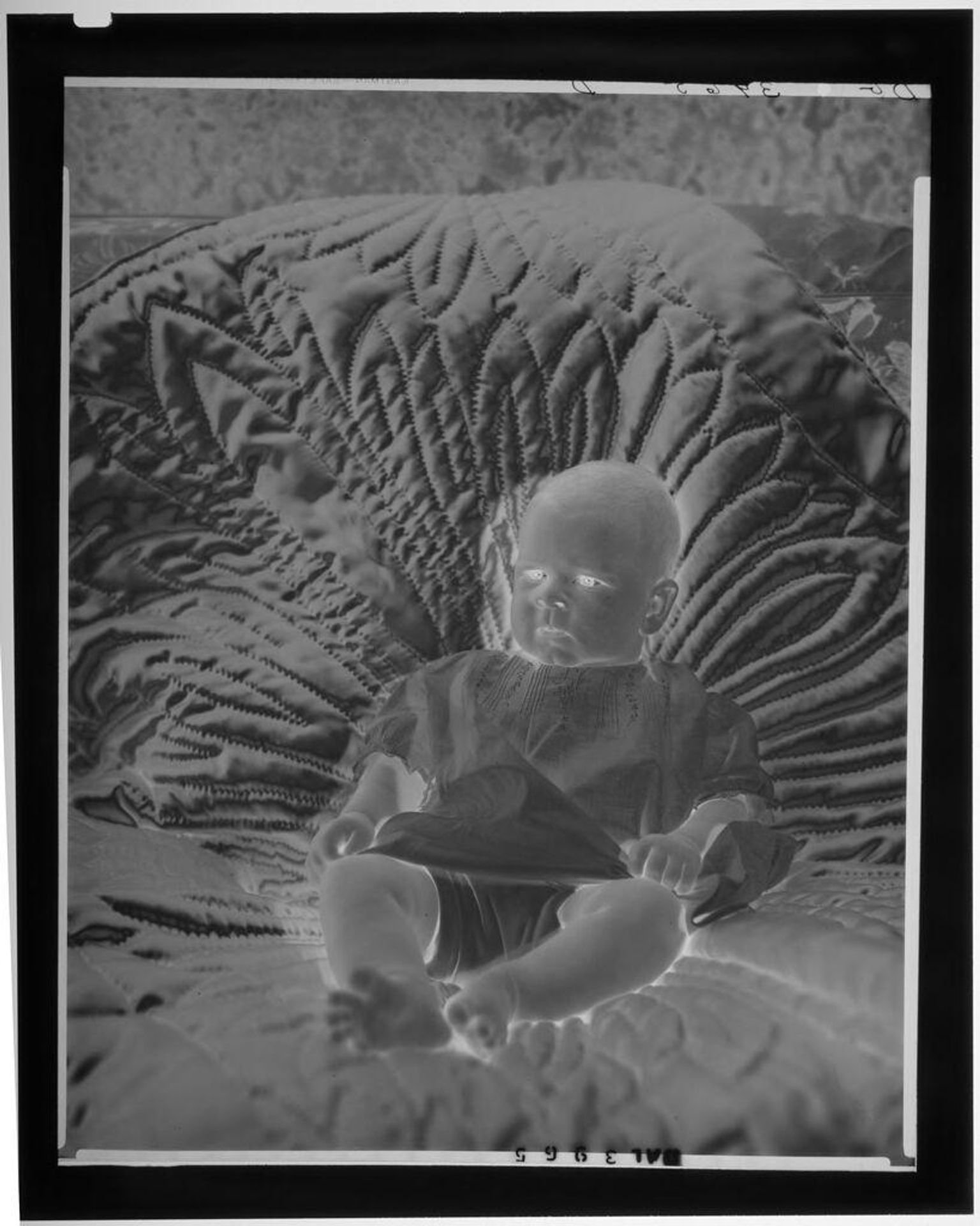 Untitled (baby leaning back on quilt) by Paul Gittings