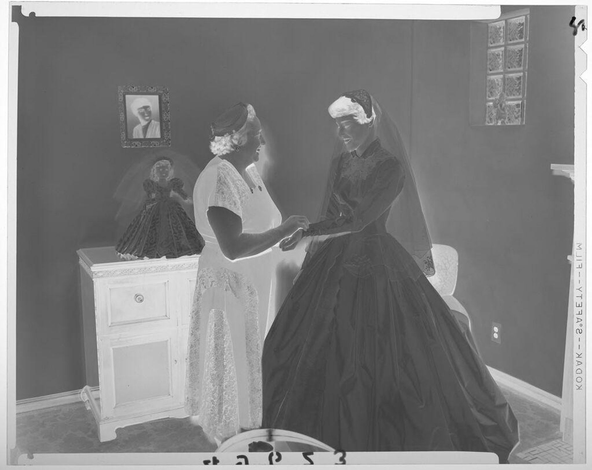 Untitled (older woman adjusting bride's sleeve in room with bride doll on dresser) by Martin Schweig