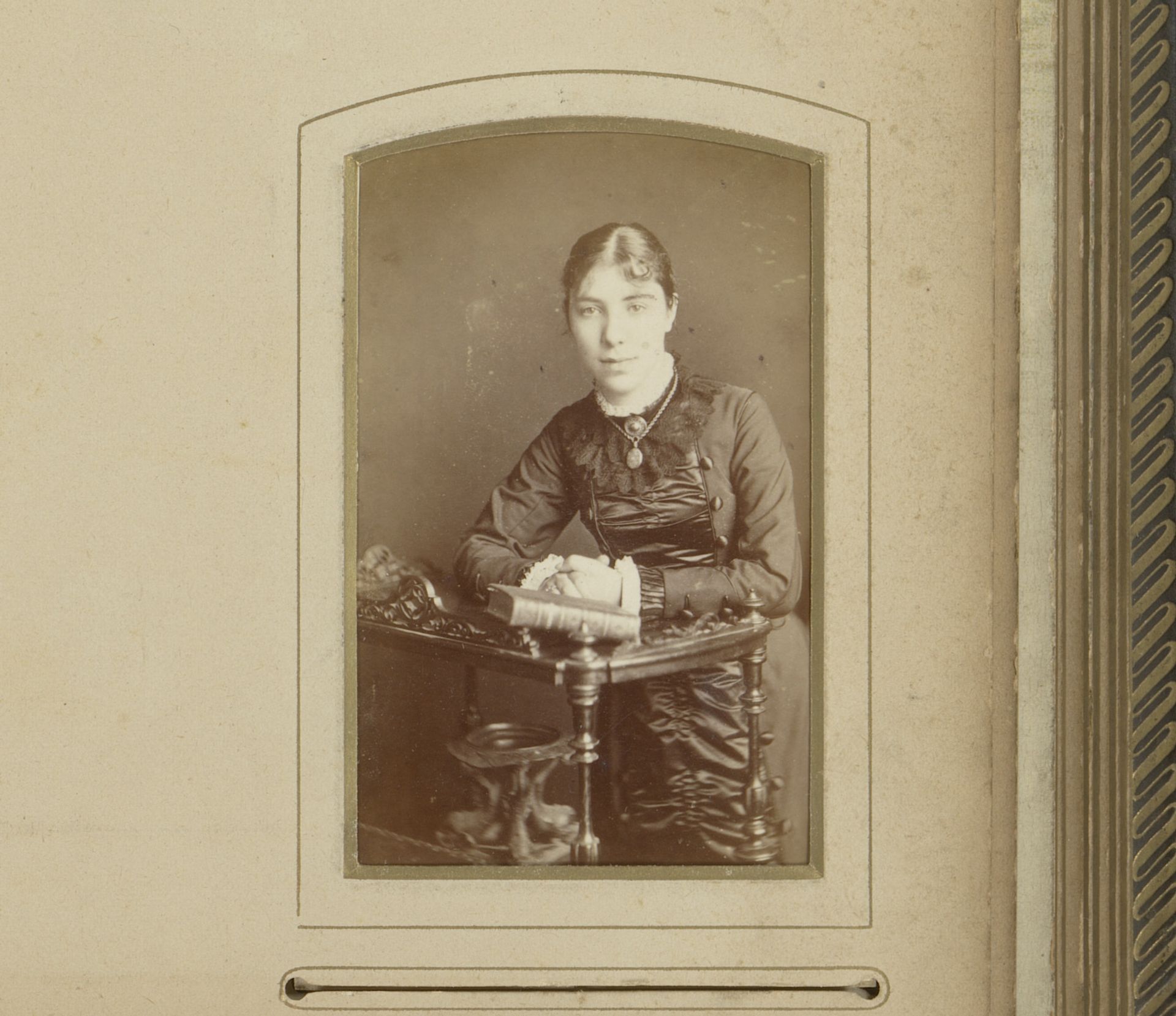 Portret van een staande jonge vrouw, leunend op een tafel met boek by Arthur Nicholls