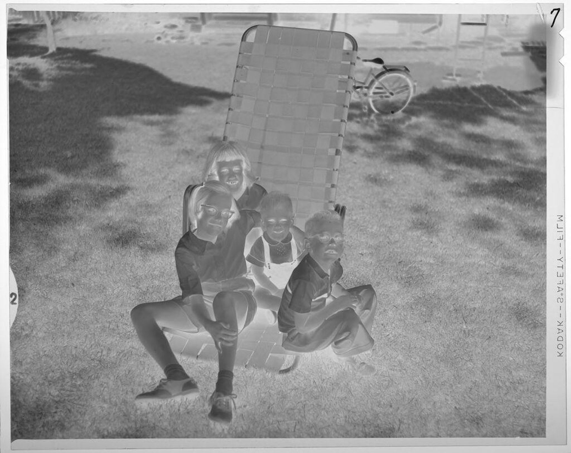 Untitled (children sitting on folding-chair on lawn) by Lucian and Mary Brown
