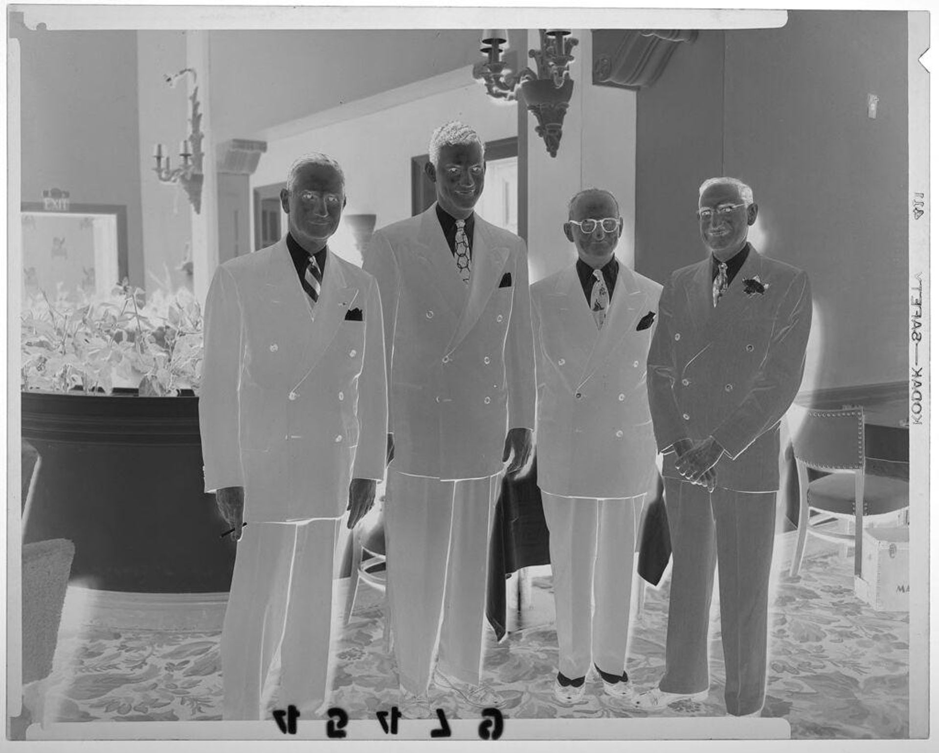 Untitled (four men posed by partition with plants at party) by Martin Schweig