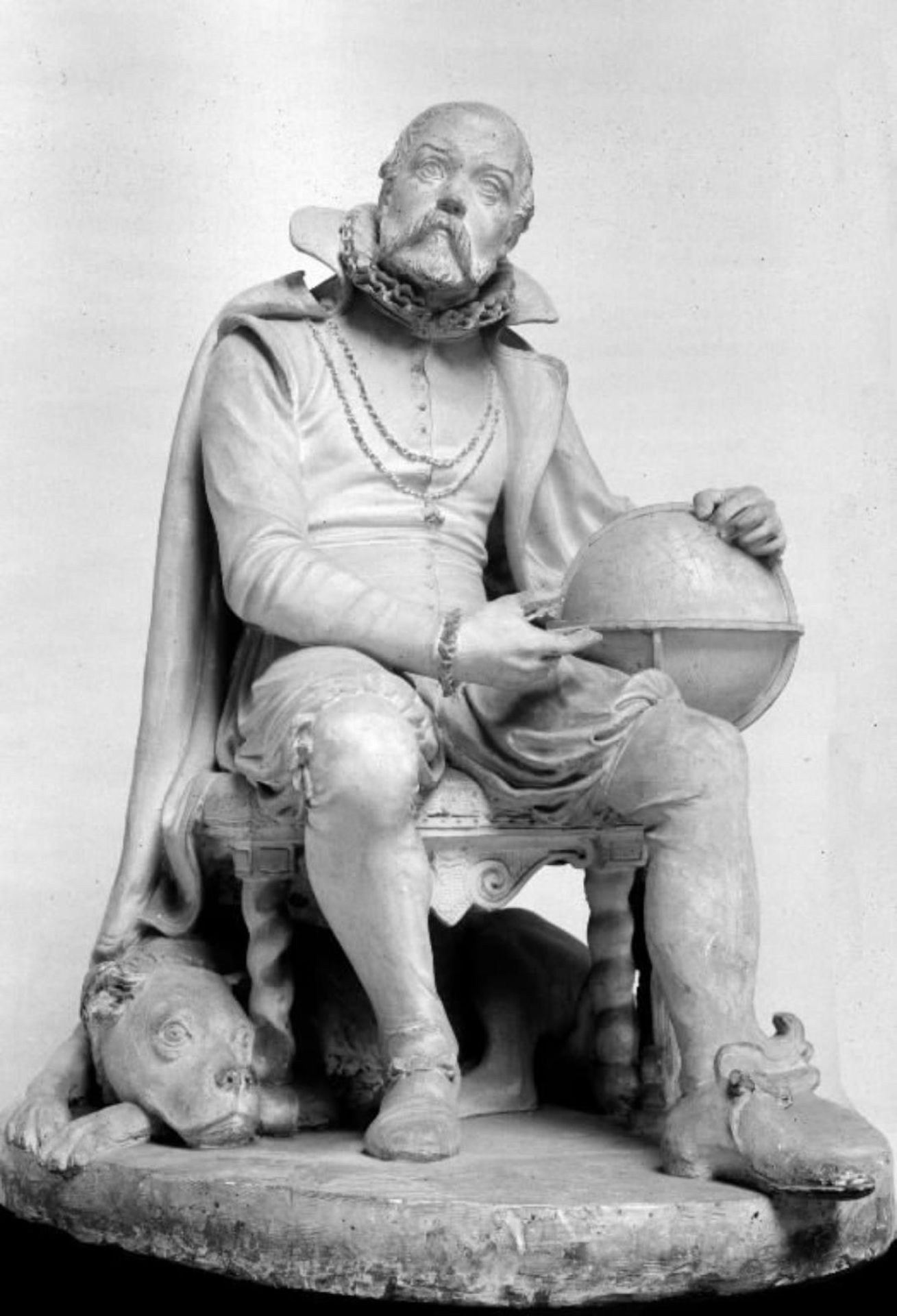 Astronomen Tycho Brahe siddende i en stol med en stjerneglobus ved siden; under stolen ligger en hund by O. Evens