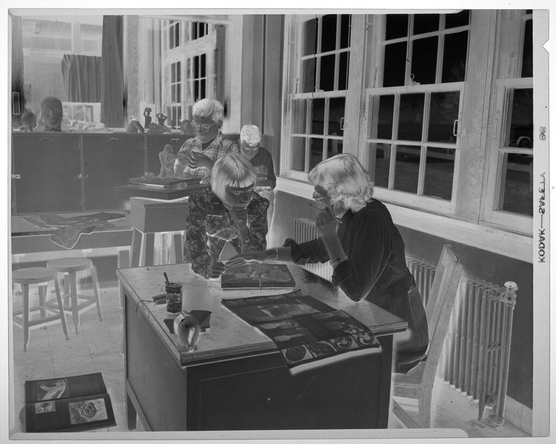Untitled (female student showing ceramic work to teacher in classroom with two male students working behind them) by Martin Schweig
