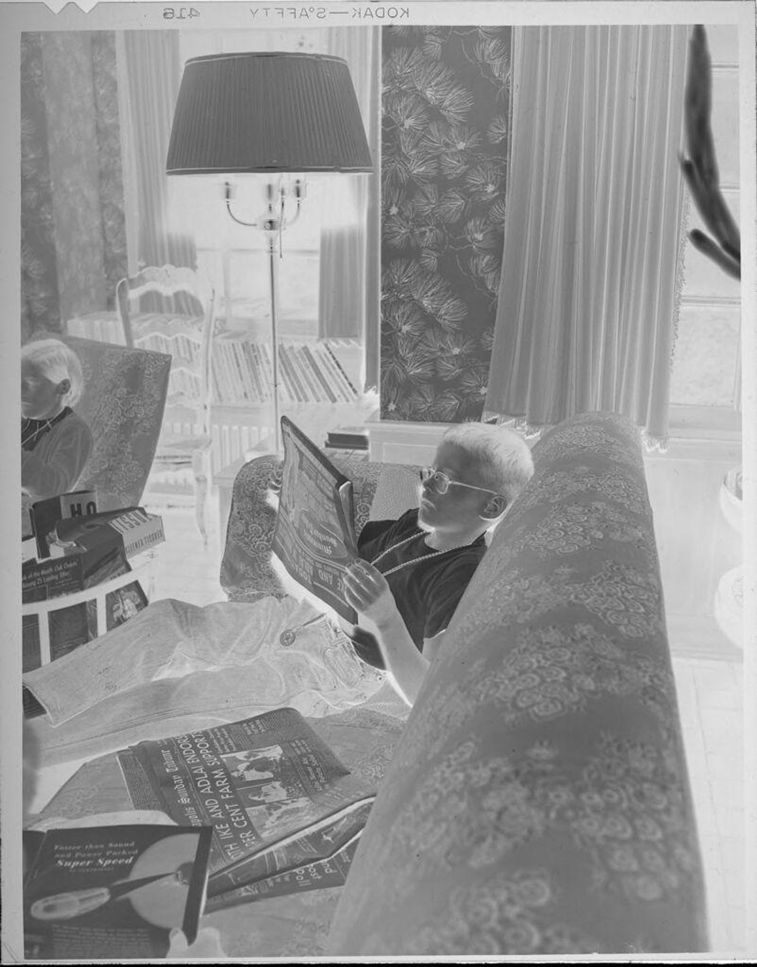 Untitled (boy reading newspaper on couch) by Lucian and Mary Brown