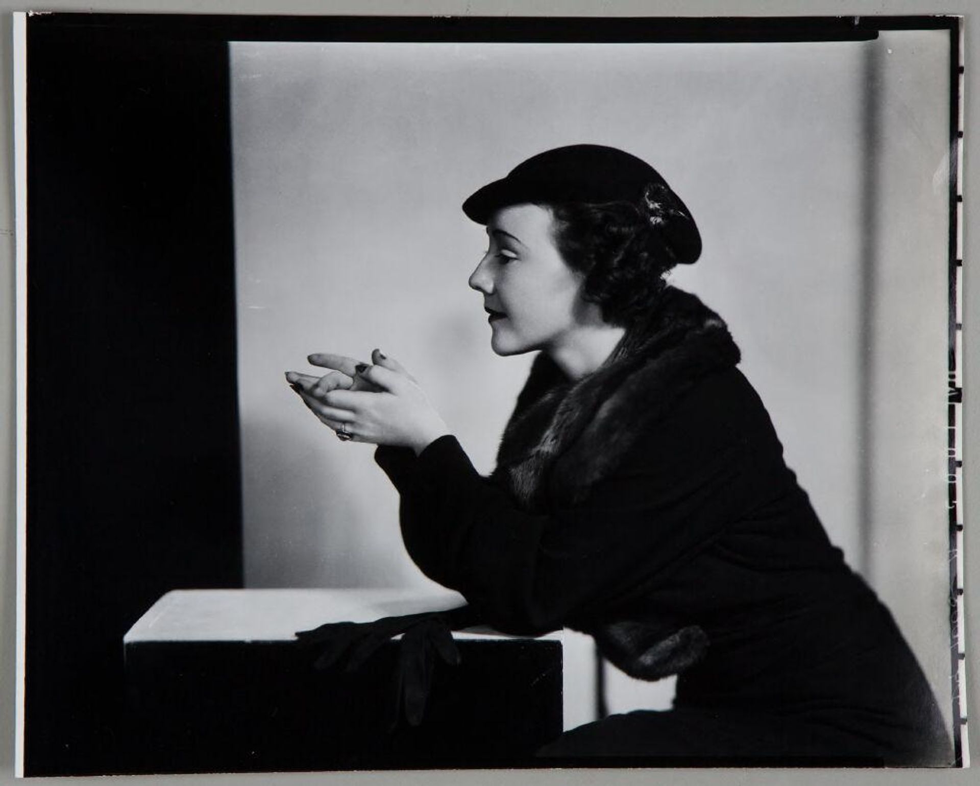 Untitled (profile portrait of woman in fur stole and hat leaning forward on elbows, gloves on prop) by Paul Gittings