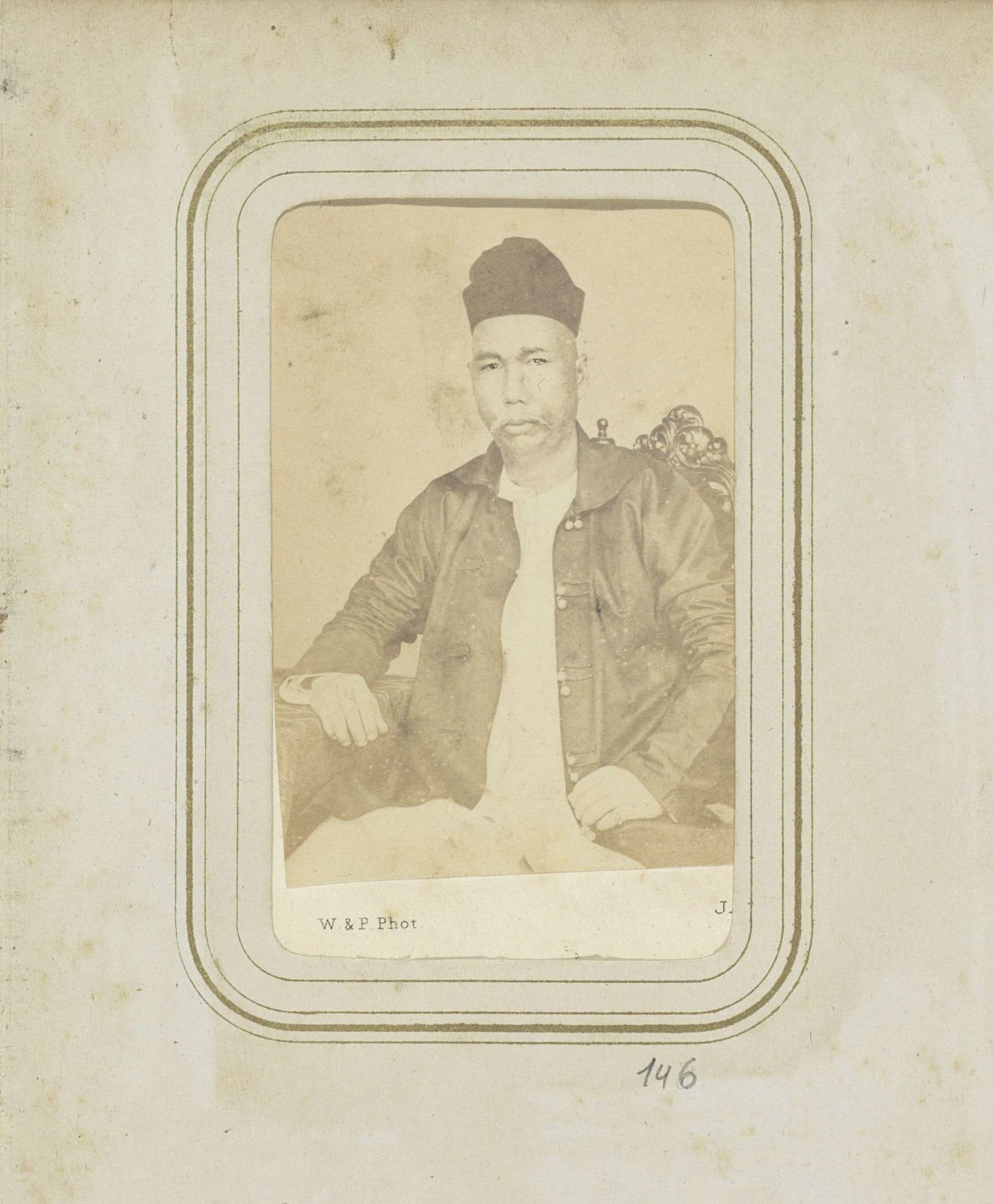 Portret van een man in een jas met een hoofddeksel by Woodbury & Page