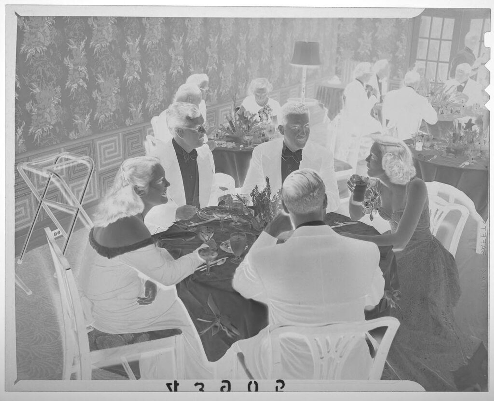 Untitled (guests chatting at dinner table during formal party) by Martin Schweig