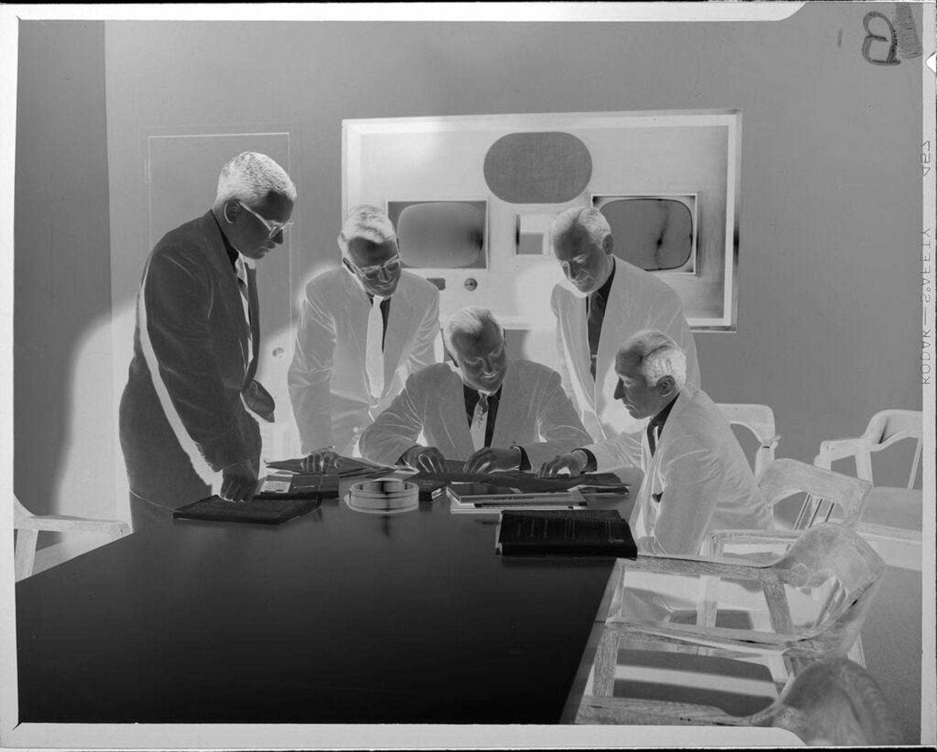 Untitled (men having meeting in room with televisions) by Peter James Studio