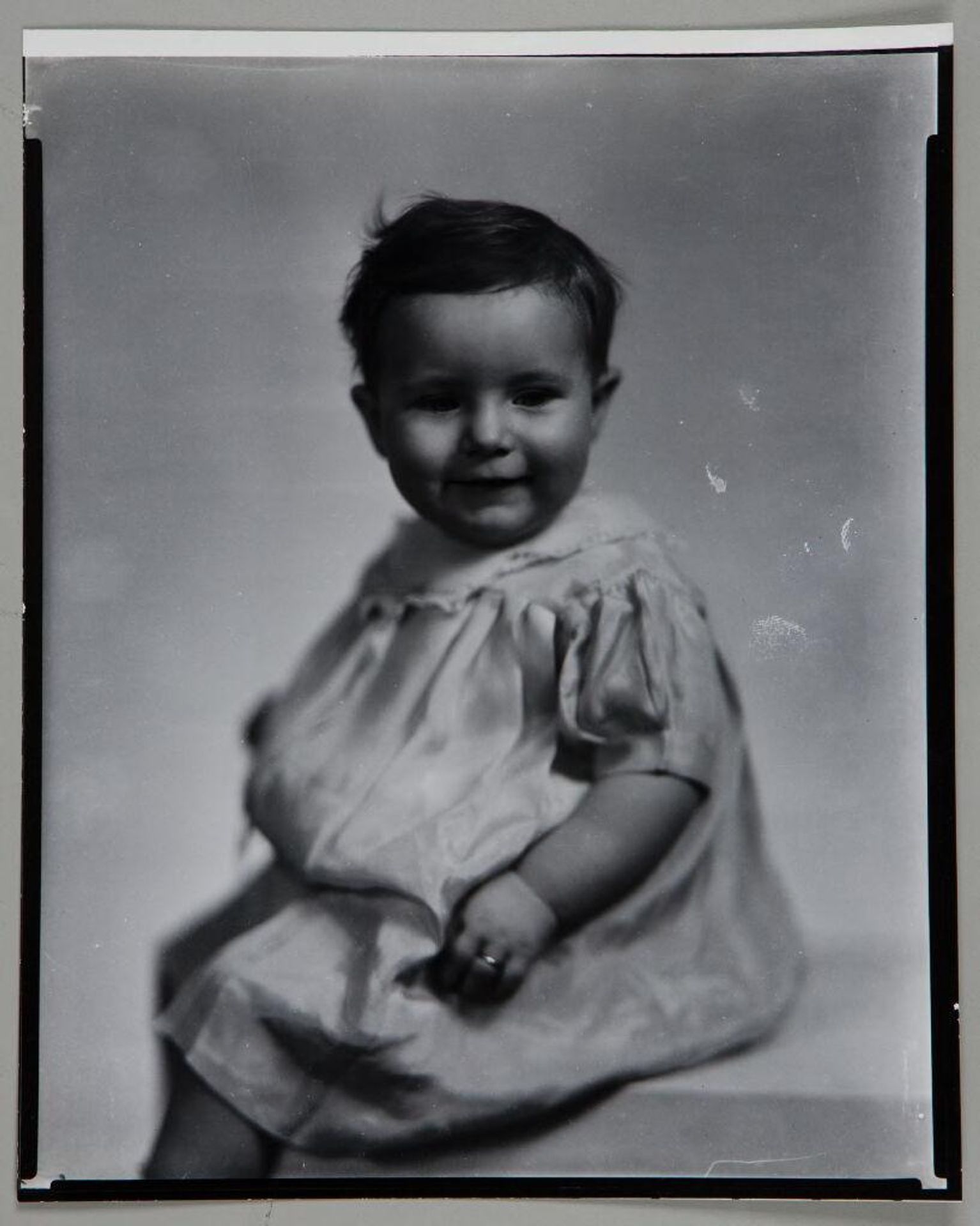 Untitled (portrait of baby, looking down, with ring on finger) by Paul Gittings