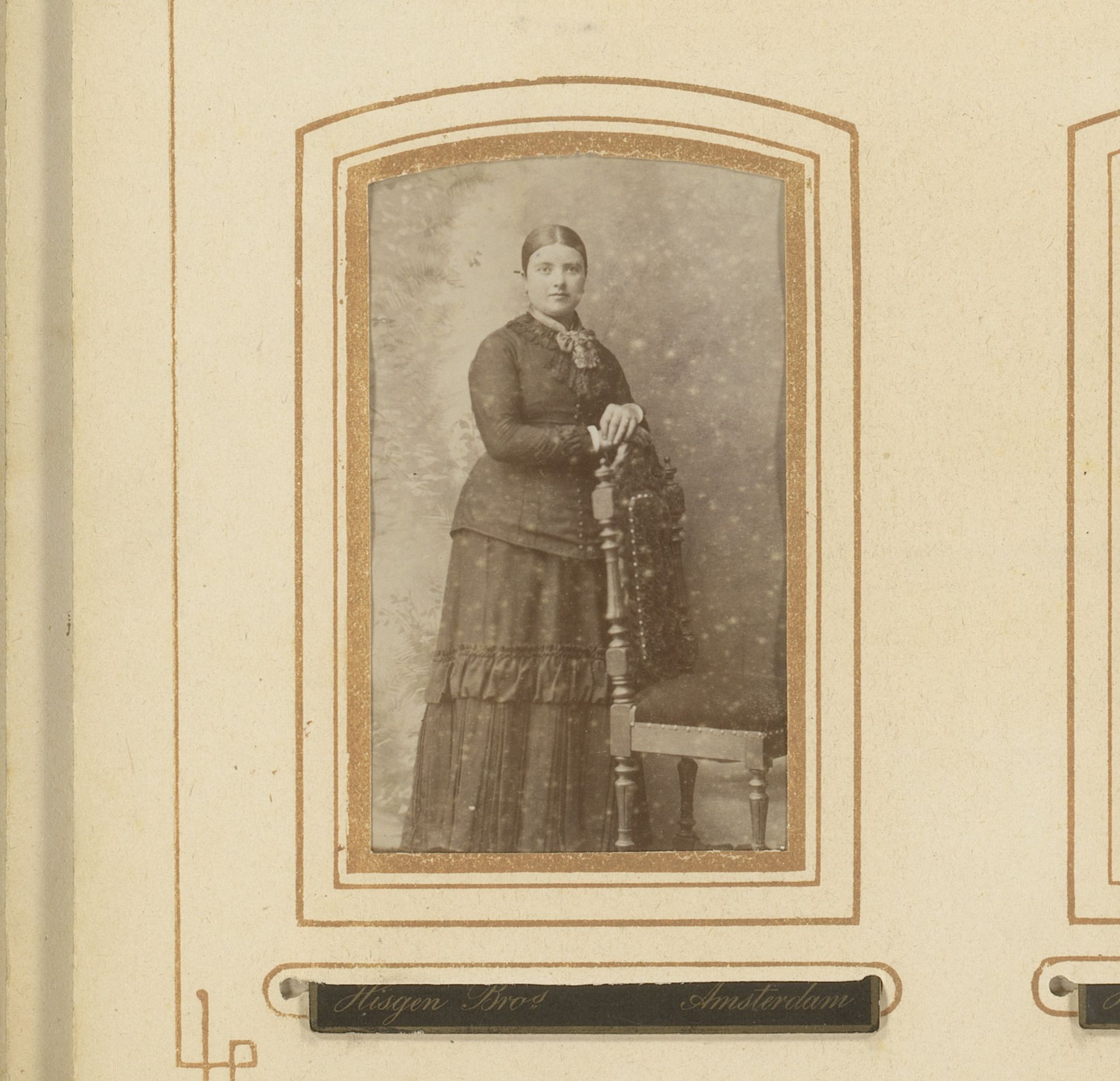 Portret van een staande vrouw bij een stoel by Hisgen Brothers