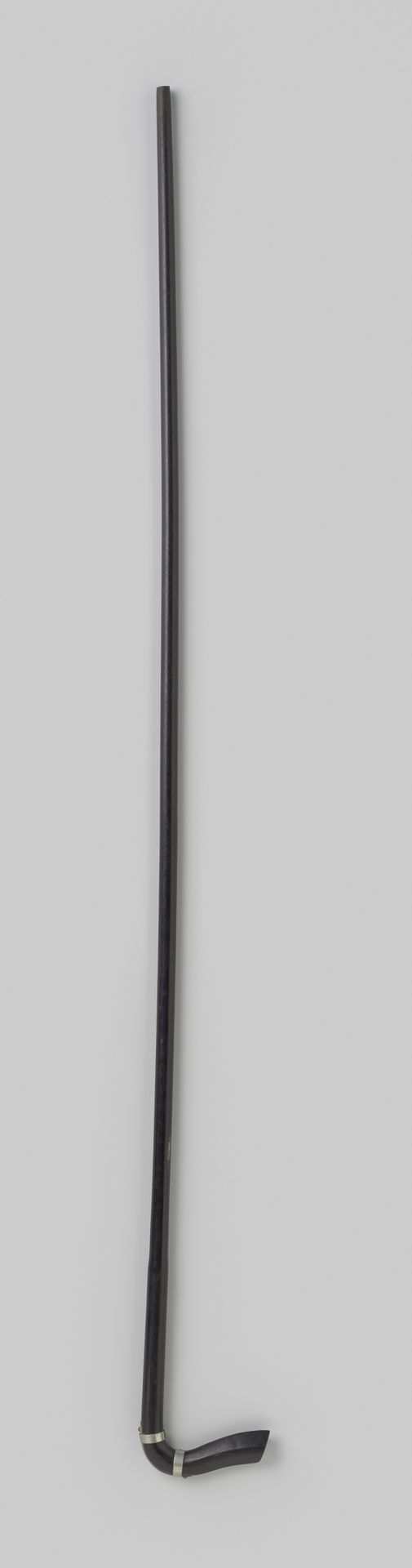 Onderstok van een paraplu of parasol van zwart geverfd hout met een gekromde haak, voorzien van twee zilverkleurige metalen ringen by Gustav Schnitzler