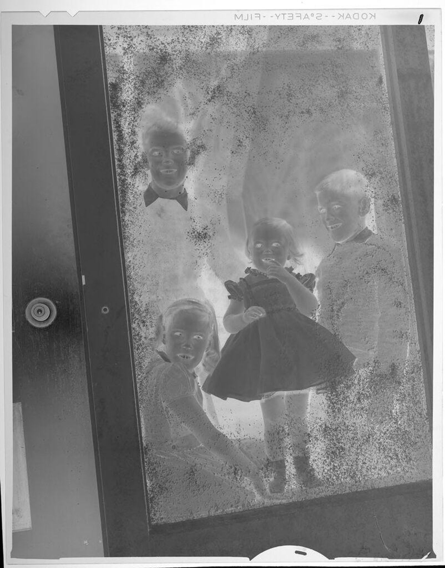 Untitled (children standing behind screen door) by Lucian and Mary Brown