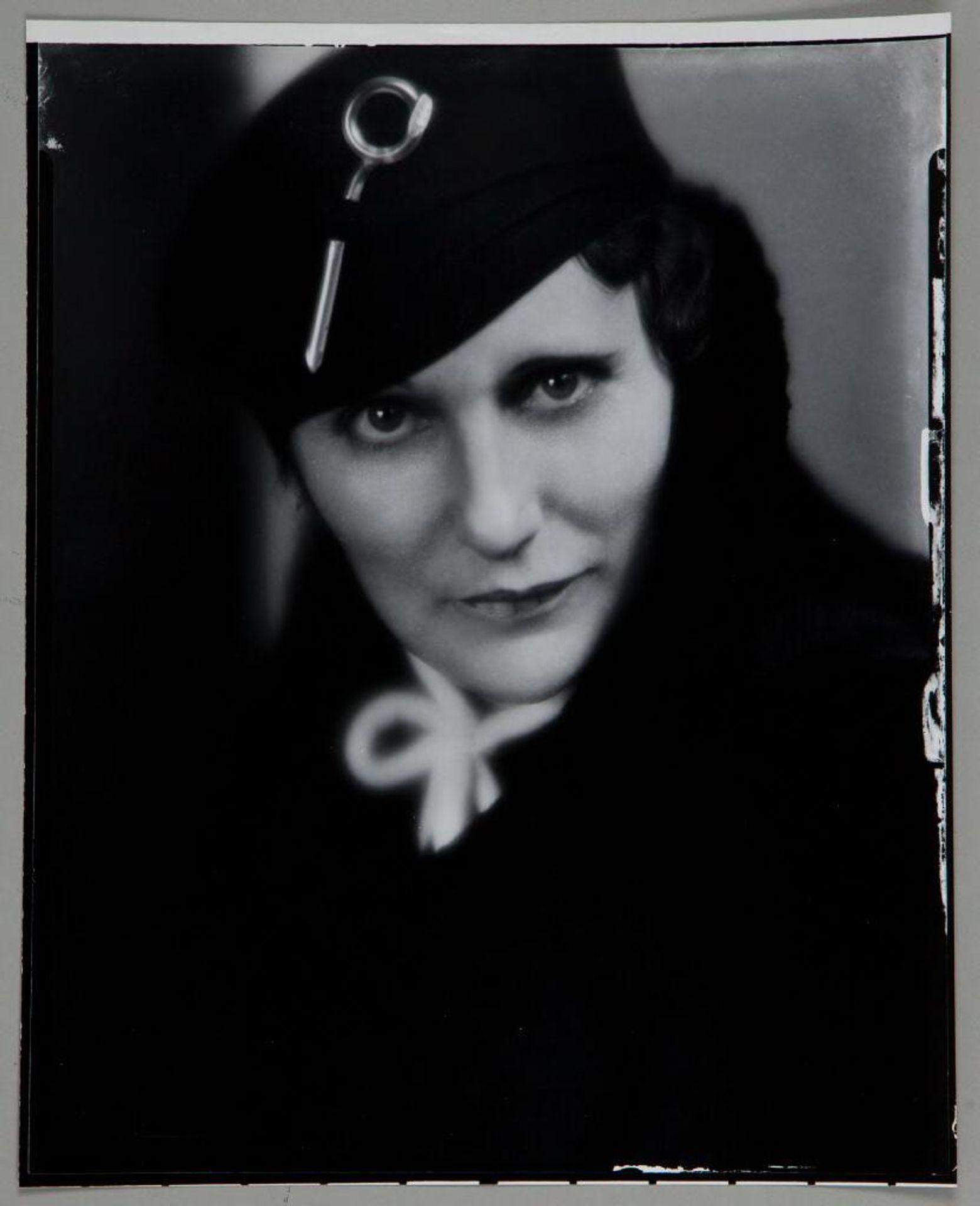 Untitled (portrait of woman in black coat with abstract silver pin in black hat) by Paul Gittings