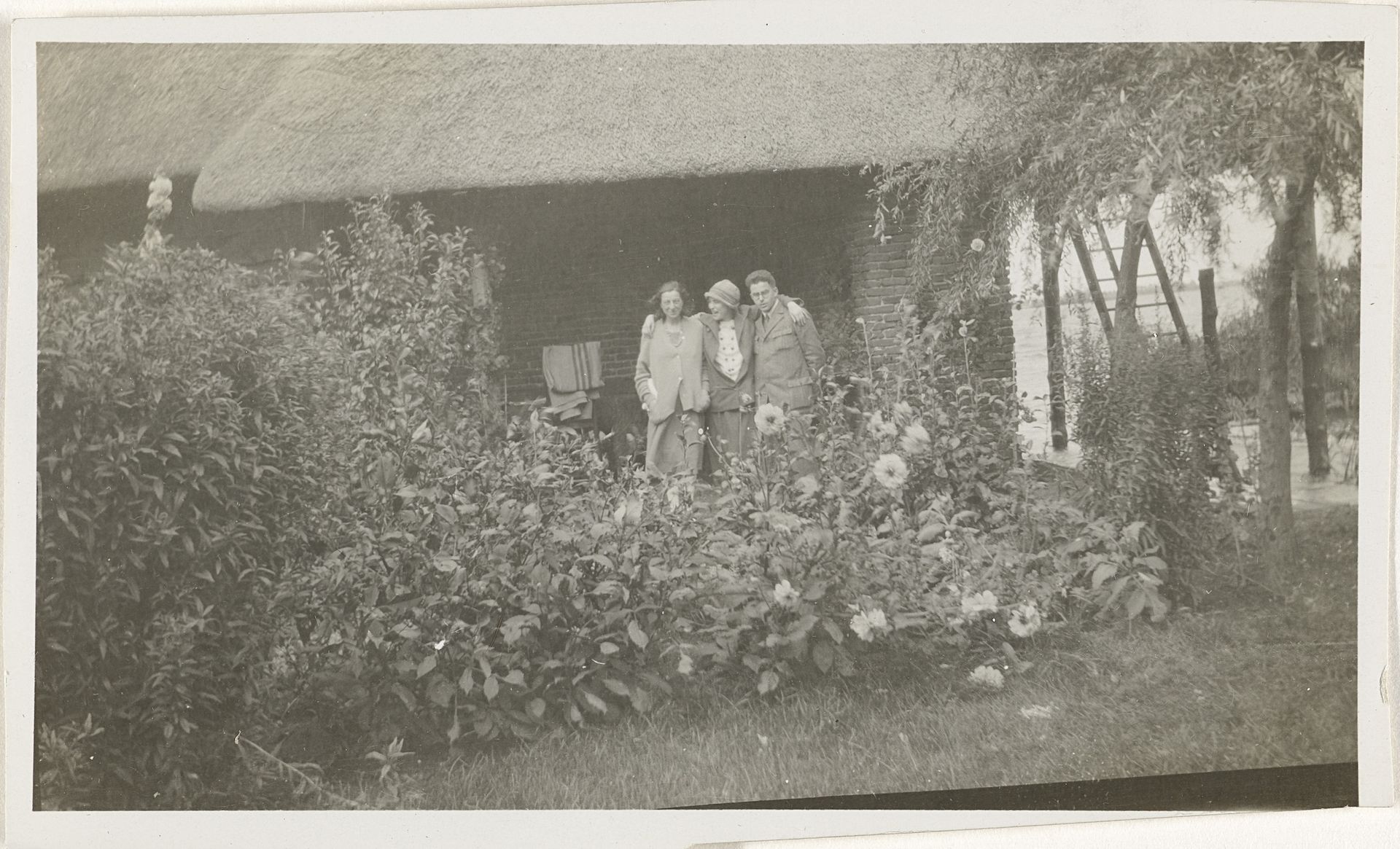 Irene With met twee onbekende personen in een tuin by Anonymous