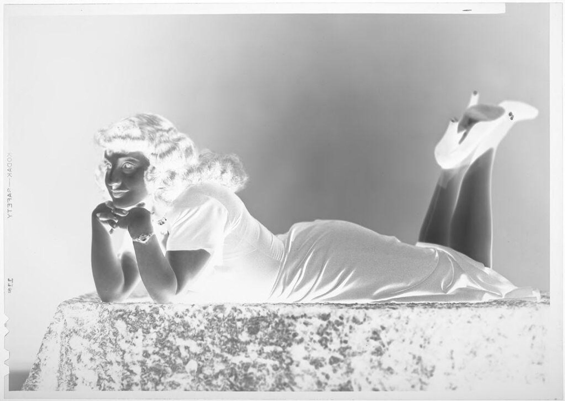 Untitled (woman lying on table, chin on hands) by John Deusing