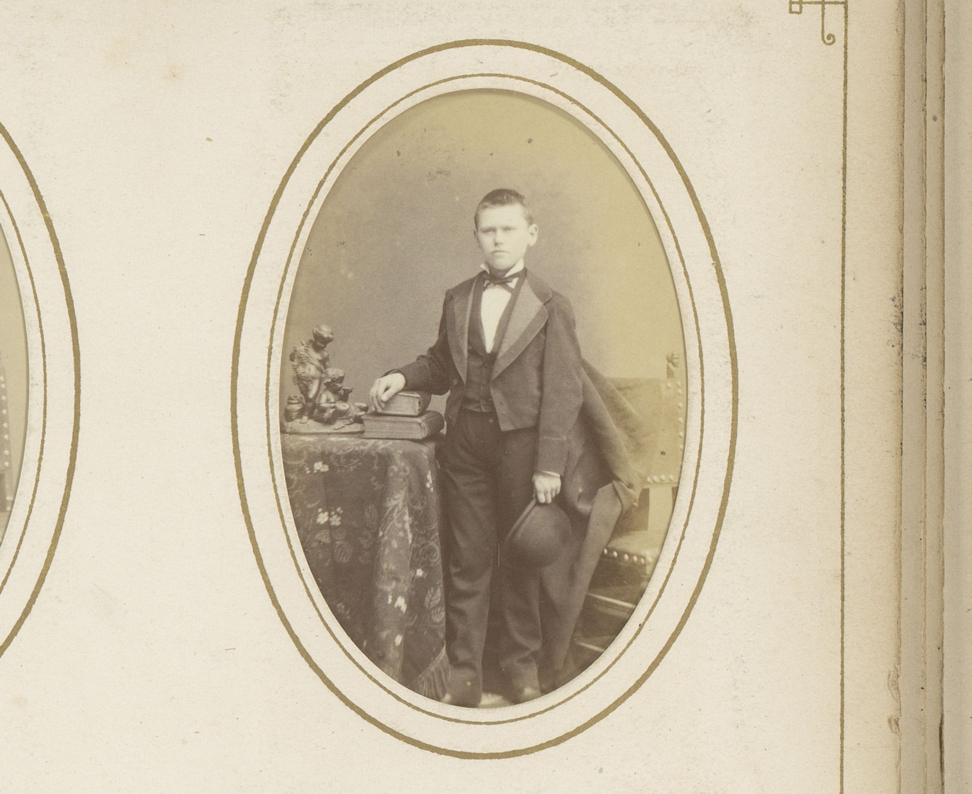 Portret van een jongen met hoed in de hand, staand tussen een tafel met boeken en een stoel by Eugene Guérin