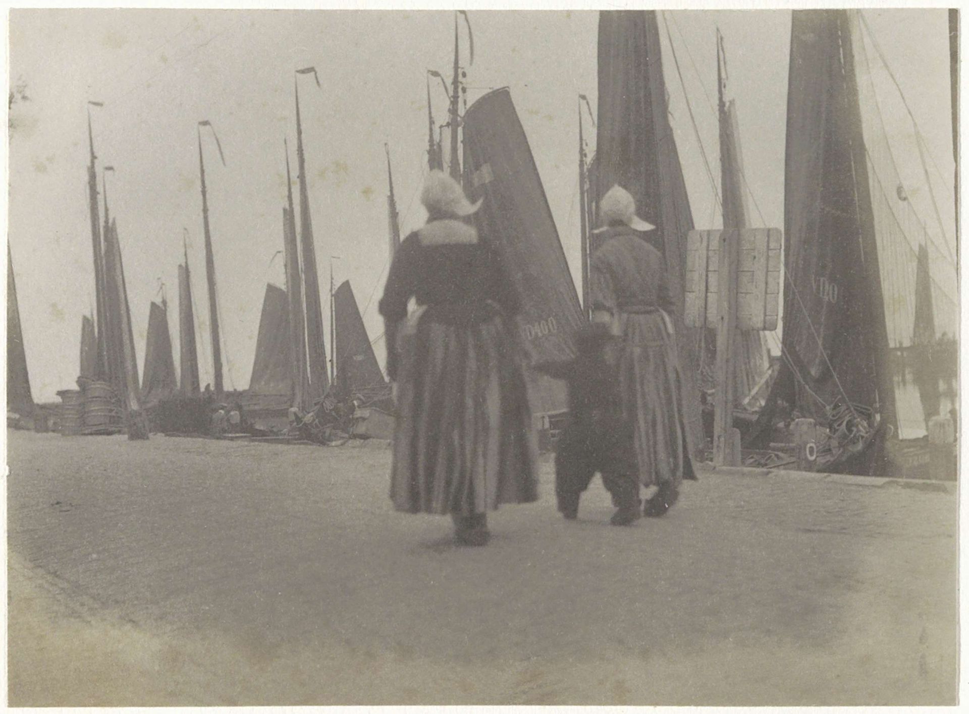 Vrouwen en jongen in klederdracht op een kade in Volendam by G. Hidderley