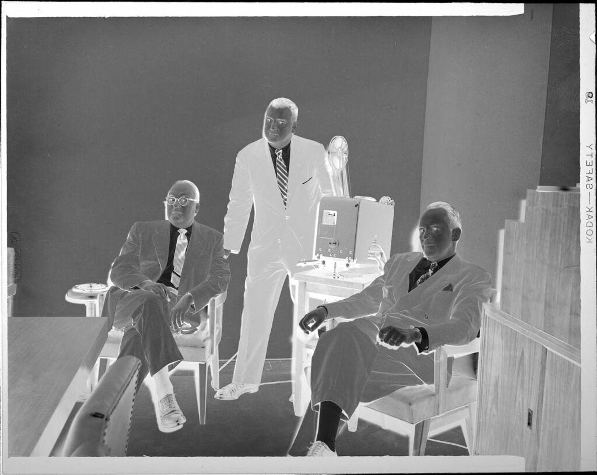 Untitled (three men with film projector) by Peter James Studio